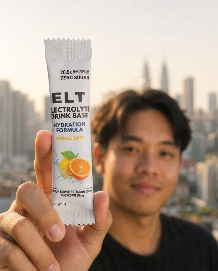 ELT sachet held up to the camera against a soft-focus Kuala Lumpur skyline at golden hour